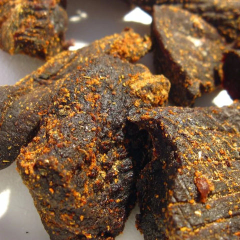 Riley's Jerky showcasing their hearty seasoned beef jerky pieces with a textured surface. The jerky appears rich, thick, and full of bold flavors.