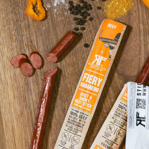 Opened habanero beef stick surrounded by spices, representing the spicy and flavorful nature of our beef stick collection.