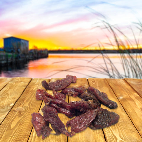 alligator jerky on wooden table at sunset lake view