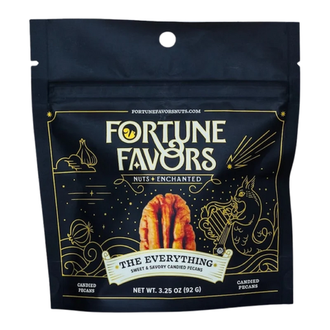 Bag of Fortune Favors 'The Everything' sweet & savory candied pecans. The packaging is dark with gold celestial and mystical illustrations, featuring a central image of a pecan and the tagline 'Nuts Enchanted.