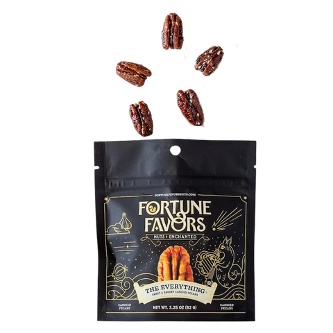 Bag of Fortune Favors 'The Everything' sweet & savory candied pecans with five seasoned pecans floating above. The dark packaging features celestial gold illustrations and a central image of a pecan under the tagline 'Nuts Enchanted.'
