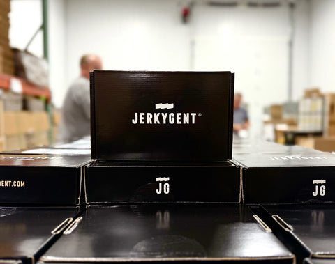 Jerkygent boxes stacked on a table in the jerkygent warehouse with the team packing boxes in the background.