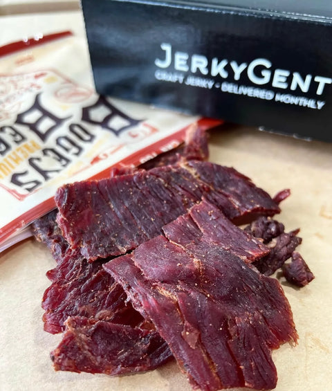 Fresh smoked beef jerky in a pile next to a Jerkygent jerky of the month club box