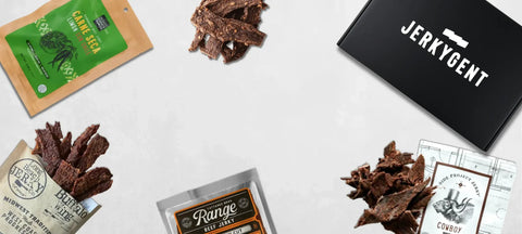 Assorted jerky packages and a beef jerky subscription box labeled 'Jerkygent' on a white surface.