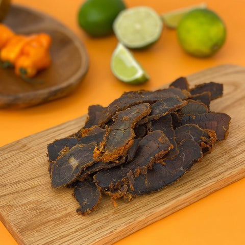 A close-up photo of the jerky in a pile on a cutting board to showcase the unique style and look of biltong jerky