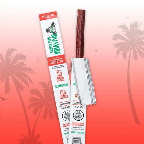 Unwrapped Baja Vida Street Taco Beef Stick on tropical palm background – 1 oz gluten-free, high-protein snack made with 100% all-natural beef, 1g sugar, 8g protein.