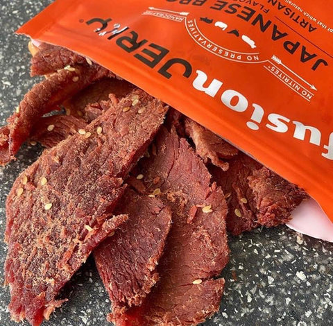 A close-up photo of Fusion Jerky Japanese BBQ coming out of the bag to feature the tenderness of the meat
