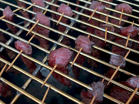 Beef jerky hanging in a smoker, infusing smoky flavors during the drying process.