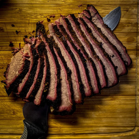 Juicy, slow-smoked brisket beef sliced on a wooden table, showcasing its rich marbling, deep BBQ char, and tender, flavorful texture.