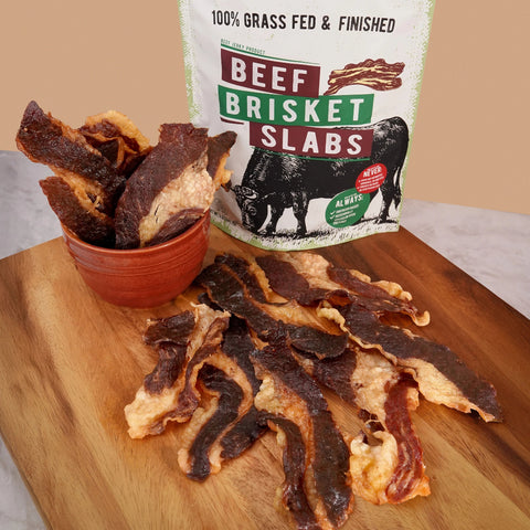 Beef brisket slabs on a wooden cutting board with a package labeled 'Beef Brisket Slabs' in the background.