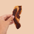 Hand holding a piece of Grazly Beef Brisket Jerky