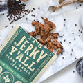 It's Jerky Yall opened with vegan jerky on a table surrounded by black pepper.