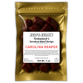 Jed’s Jerky “Timberjack’s Smoked Beef Strips” in the Carolina Reaper flavor. The front features a horizontal white label with bold black retro lettering for “Jed’s Jerky,” followed by “Timberjack’s Smoked Beef Strips” and “Carolina Reaper” in bright red. The label includes a full ingredients list, net weight, and storage instructions. Through the clear window, thick, juicy, hand-cut beef chunks are visible, showcasing a rich, dark reddish-brown color.