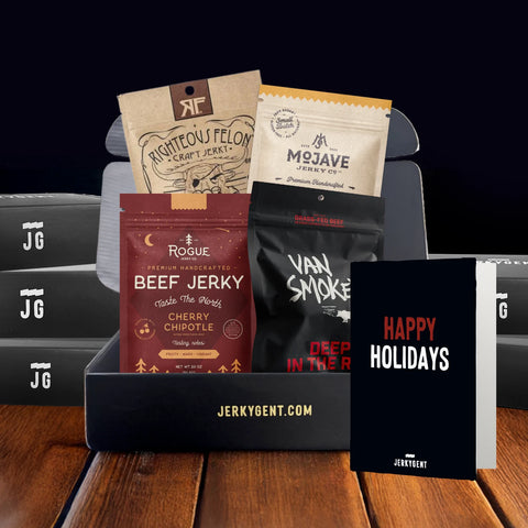 Assorted bags of beef jerky and a 'Happy Holidays' card on a wooden surface with a black background.