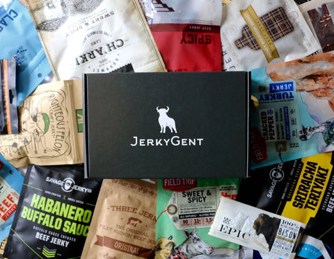 JerkyGent Beef Jerky Subscription Box on top of a pile of different craft beef jerky brands