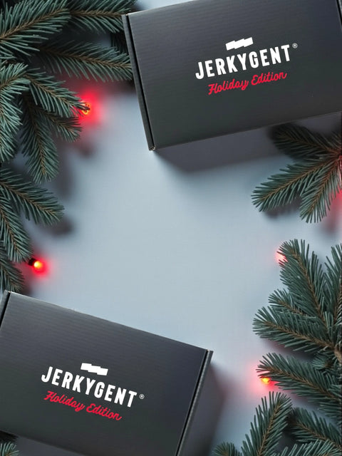 Two black boxes labeled 'Jerkygent Holiday Edition' surrounded by Christmas tree branches and lights on a light gray background.