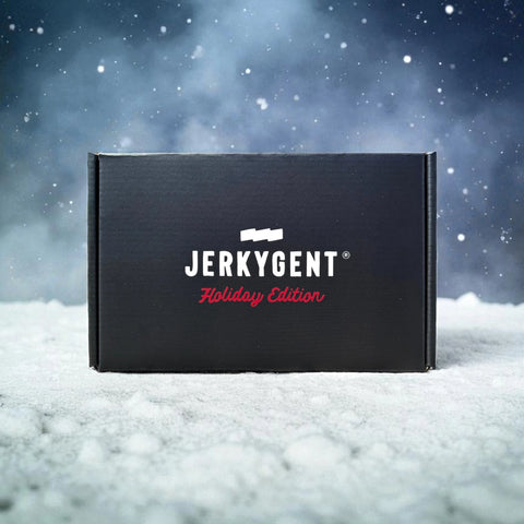 Black JerkyGent Holiday Edition gift box sitting on snowy ground with falling snow and frosty winter background.