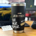 Black stainless steel JerkyGent Yeti tumbler on a desk, featuring the JerkyGent logo and two stickers that say “EAT. MEAT. REPEAT.” and “BEST. CLUB. EVER.” with a “Powered by Jerky” sticker in the background.
