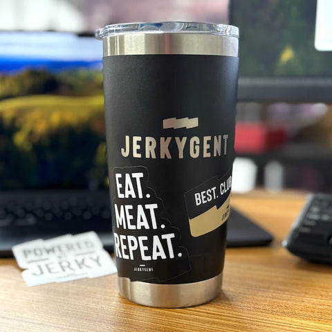 Black stainless steel JerkyGent Yeti tumbler on a desk, featuring the JerkyGent logo and two stickers that say “EAT. MEAT. REPEAT.” and “BEST. CLUB. EVER.” with a “Powered by Jerky” sticker in the background.