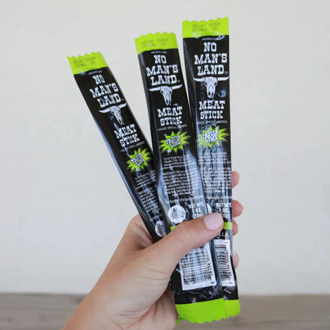 Hand holding three No Man’s Land Fajita Lime Meat Sticks, 1 oz each.