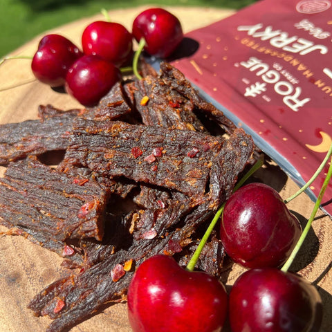 A close-up image of the jerky to show the infused spices and seasonings along with some Traverse City, MI cherries