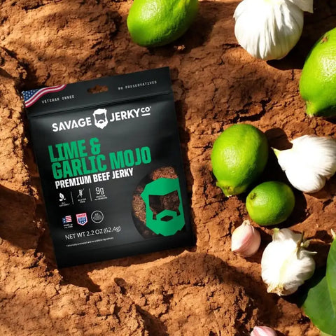 Savage Jerky Co. Lime & Garlic soft beef jerky in the soil with limes and garlic cloves