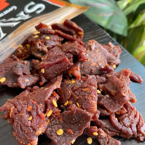 A close-up photo of Hot BBQ brisket jerky from Savor Ranch, which shows the infused peppers and spices along with the tenderness of the brisket jerky