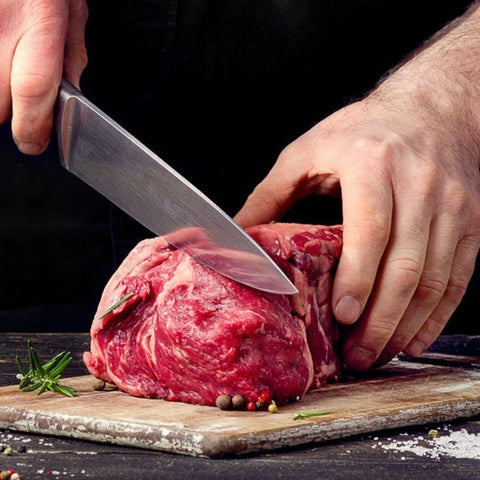 A photo of someone using a knife to slice into a large hunk of high-quality meat