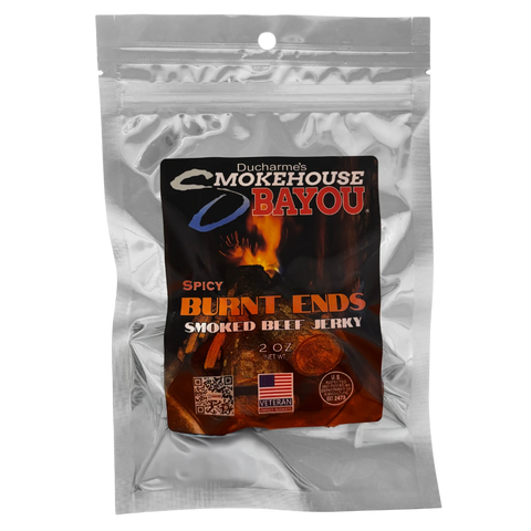 Bag of Ducharme’s Smokehouse Bayou Spicy Burnt Ends Smoked Beef Jerky, 2oz silver pouch with dark fire-themed label, veteran-owned branding.