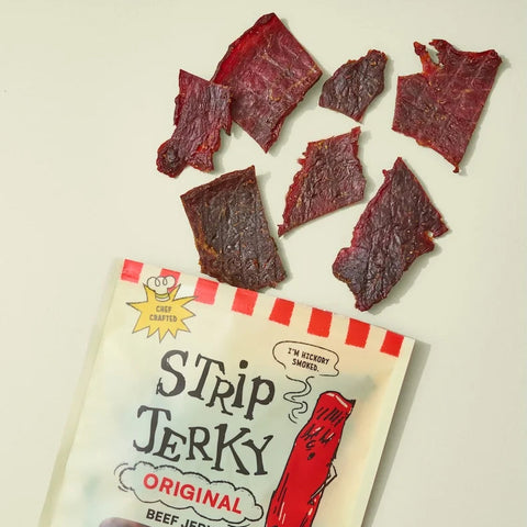 Strip Jerky packaging with beef jerky pieces on a light background