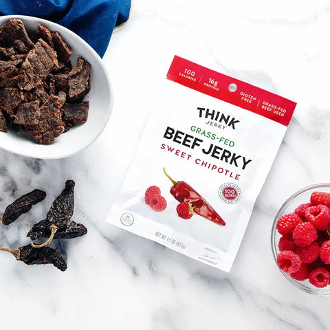 Think Jerky Sweet chipotle on a table with raspberries and peppers