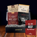 Box of beef jerky packages from various brands in a gift box with a greeting card on a wooden surface.