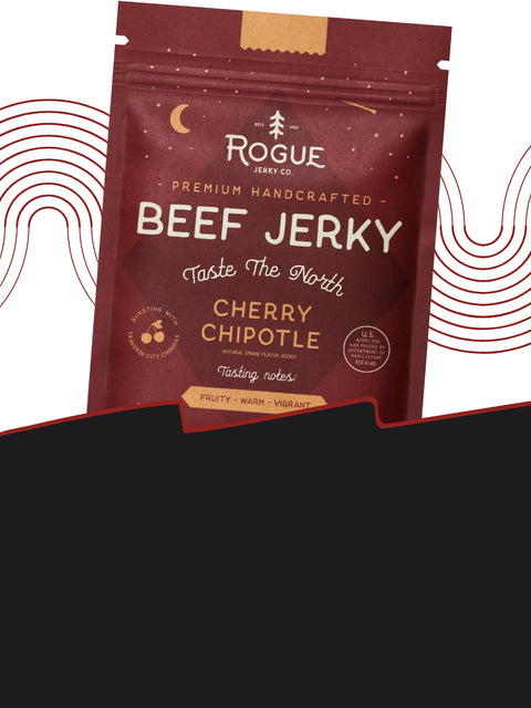 Cherry Chipotle flavor jerky from Rogue Jerky Co. in a deep red pouch. Text reads ‘Taste The North’ with tasting notes: Fruity, Warm, Vibrant. Moon and tree icons reinforce the Northern theme.