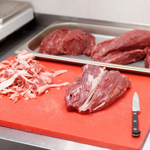 A photo of the labor intensive process of trimming fat from meat.