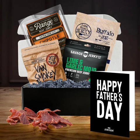 JerkyGent PrePaid Monthly Jerky Gift Box featuring a premium assortment of craft beef jerky brands including Range, Van Smokey, Long Beach Jerky Co., and Savage Jerky. Displayed in a sleek black gift box with shredded filler, slices of jerky, and a bold black 'Happy Father’s Day' card — perfect for gifting this Father's Day.
