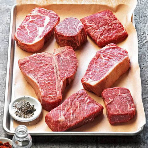 A selection of high-quality raw beef laid out on a cooking sheet.